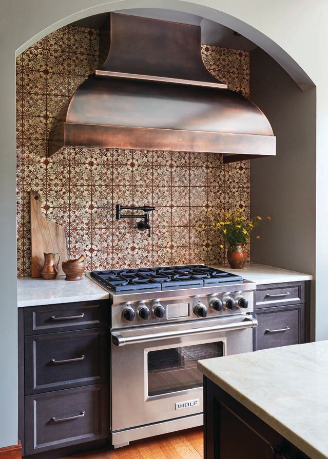 The custom vent hood, also by PB Kitchen Design, is surrounded by terra-cotta tiles from The Fine Line and a Brizo pot filler. PHOTO BY MICHAEL KASKEL