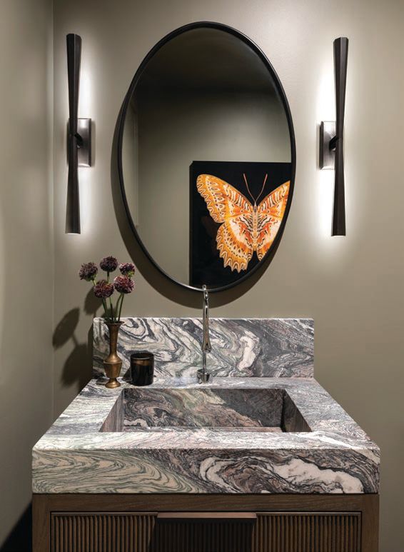 The powder room features a pair of Circa sconces, a Rejuvenation mirror, hypnotic stone from Calia Stone Boutique and the artwork “Red Wing Lace Wing” by Amy Perlmutter. PHOTOGRAPHED BY AIMÉE MAZZENGA