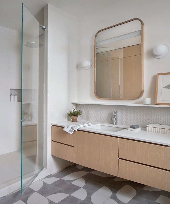 Highlights of the primary bathroom include a custom vanity by Peter Chasak, lighted mirror by MunnWorks, Pastille disc sconces in matte white by RBW and Boreal Dots floor tile in lunar by WOW Photographed by Gibeon Photography