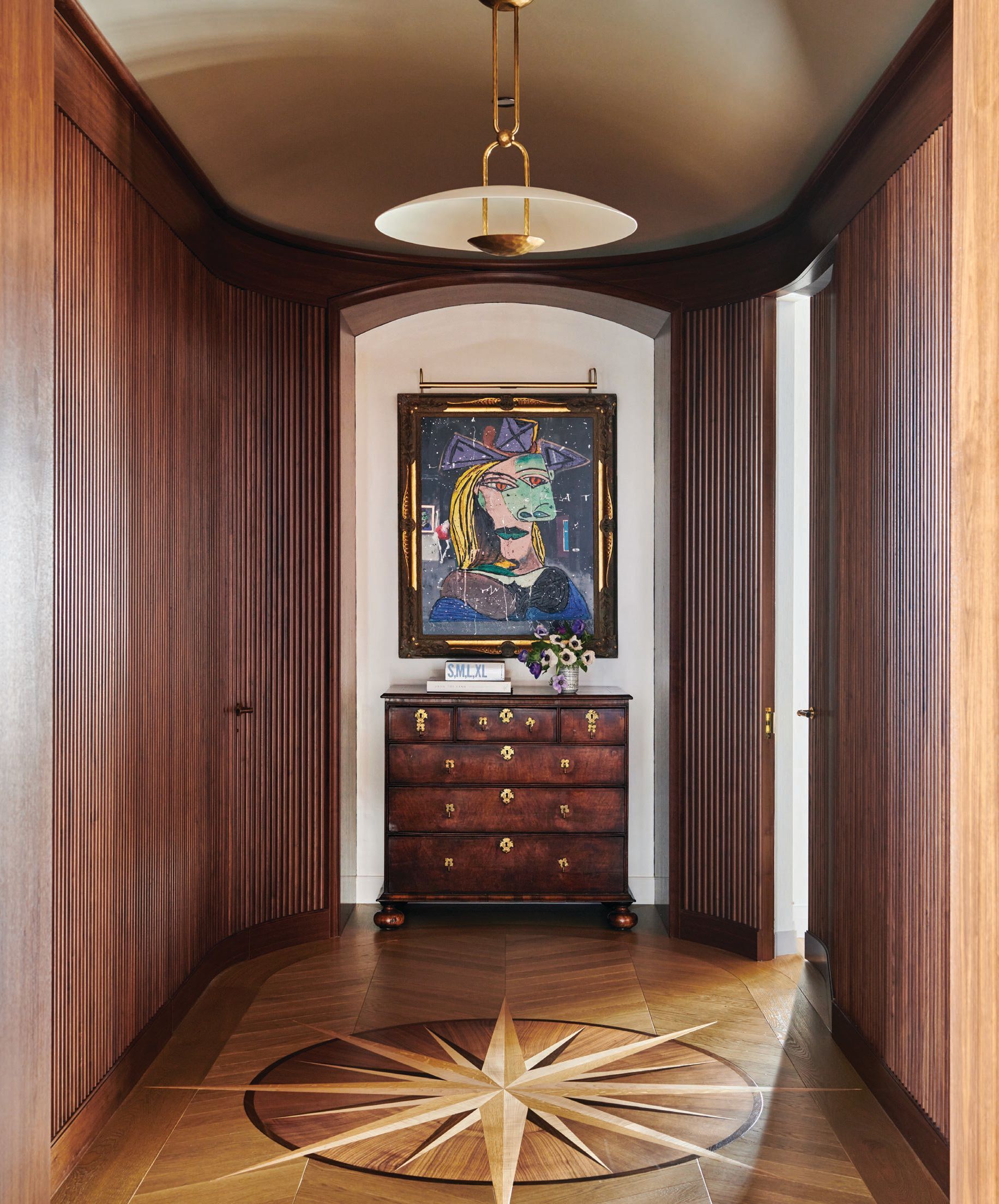 The home's east rotunda dazzles with wood paneling produced by Exclusive Woodworking and an eyecatching star floor design produced by Apex Wood Floors—both custom designed by Soucie Horner—along with the client's own credenza and a Picasso-influenced artwork by Angelo Accardi. Photographed by Richard Powers