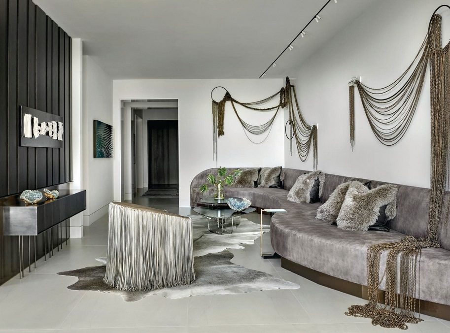Curvature in the 26-foot custom sofa presents a deeper section for lounging on one side and a shallower curve for guests to gather more intimately on the other; a custom sculptural installation made of bronze-toned beads, chains and Lucite blocks by Beth Kamhi (@beth_kamhi_artist) hangs above the sectional; a leather fringed chair from Ngala Trading completes the sultry living room look. PHOTOGRAPHED BY TONY SOLURI