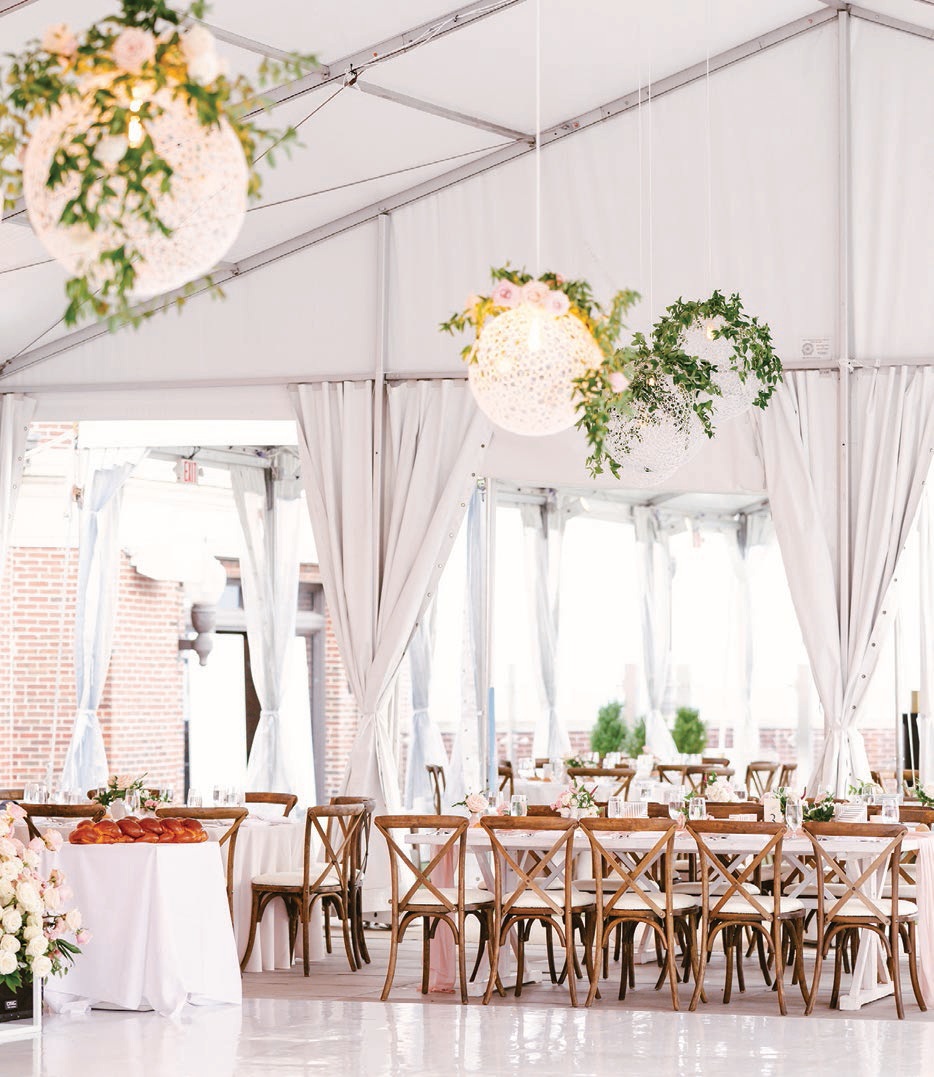 Globe lights adorned with greenery hung over the dance floor for the tented reception Photographed by Connie Marina Photography