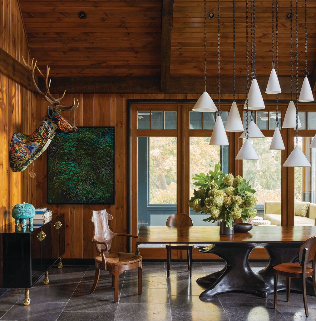 A custom chandelier made of a cluster of 12 free-blown glass cone pendants suspended from a dark axed bronze backplate and chains by Remains Lighting in the great room PHOTOGRAPHED BY ERIC PIASECKI