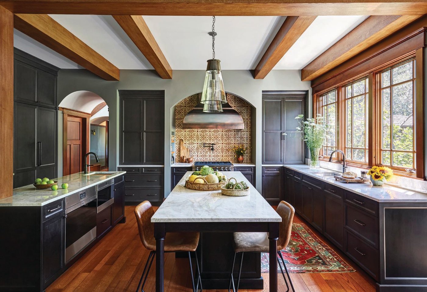 The kitchen combines light tones as seen in the Taj Mahal quartzite countertops with moodier hues a la the PB Kitchen Design cabinets. The pendants are from Circa Lighting PHOTO BY MICHAEL KASKEL