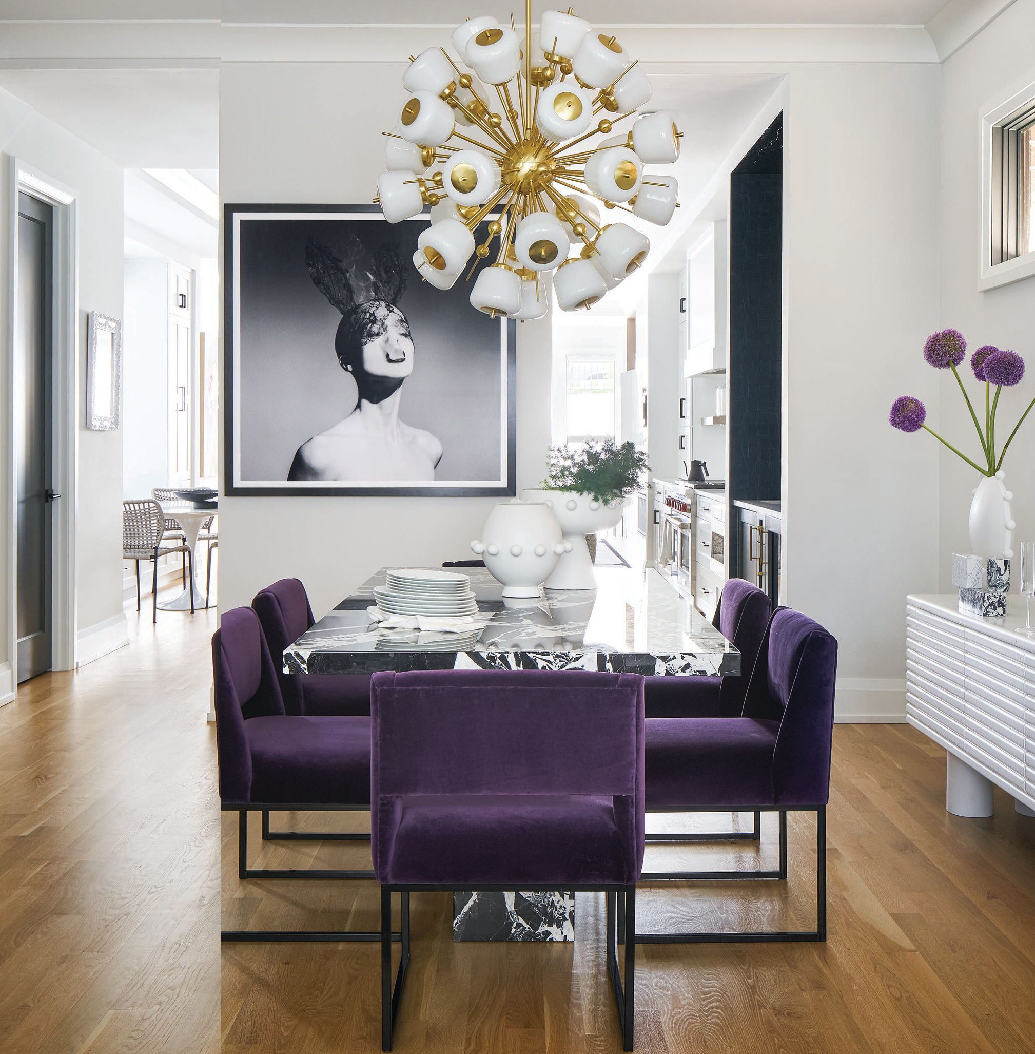 A custom marble slab table and vintage Sputnik chandelier from Venfield
in NYC add extra elegance, while bold art from Tyler Shields (@thetylershields)
and Jenna Krypell (@jennakrypellstudio) complement the room’s purple tones. PHOTOGRAPHED BY RYAN MCDONALD