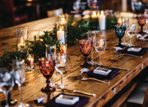 Colored glass goblets glowed on bare wood farm tables lined with runners of greenery.